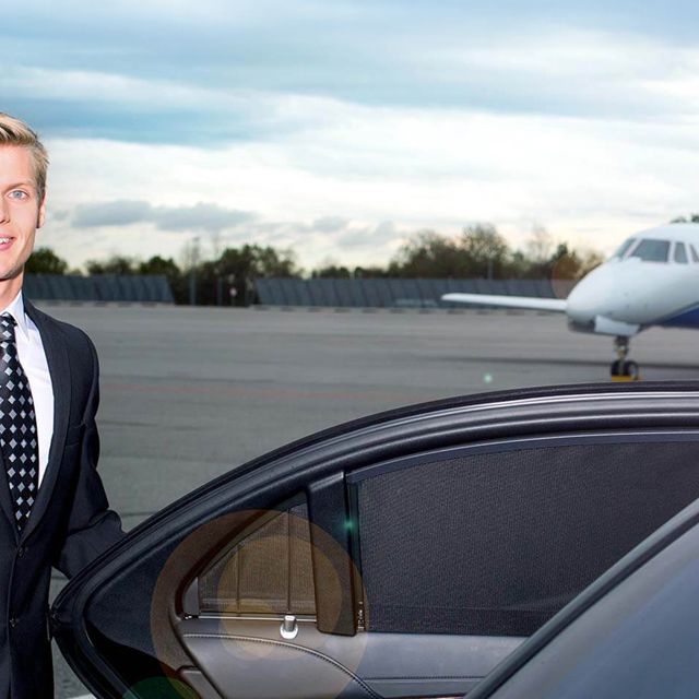 Ein Chauffeur hilft einer Frau aus einem Minivan am Flughafen.