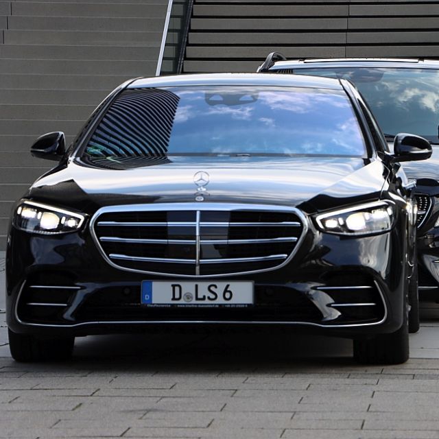 Ein Chauffeur reicht einem Fahrgast vor einem Business-Jet die Hand.