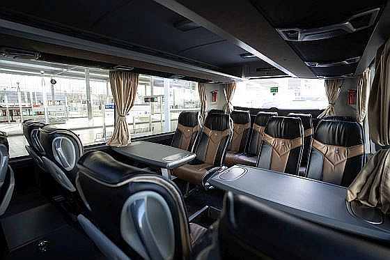 Innenraum eines VIP-Busses mit Arbeitstischen.