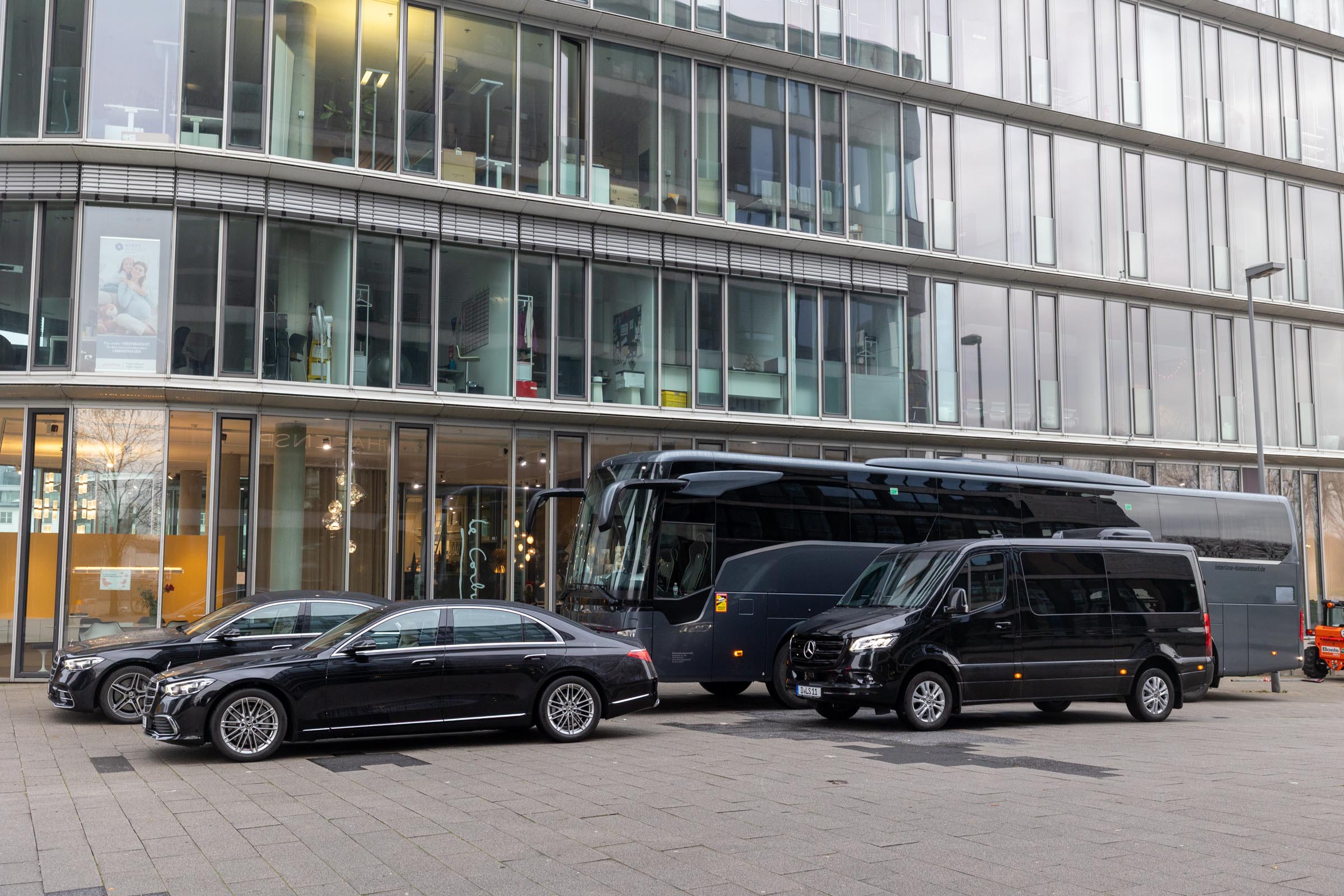 Ein Chauffeur öffnet einem Fahrgast die Tür einer Limousine auf dem Rollfeld eines Flughafens.