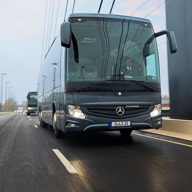 Reisebusse und ein Minivan auf dem Rollfeld vor einem Flugzeug